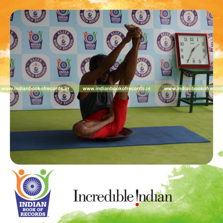 individual holding vama ardha padma krounchasana yoga pose blindfolded on a brass plate for record in Indian Book of Records