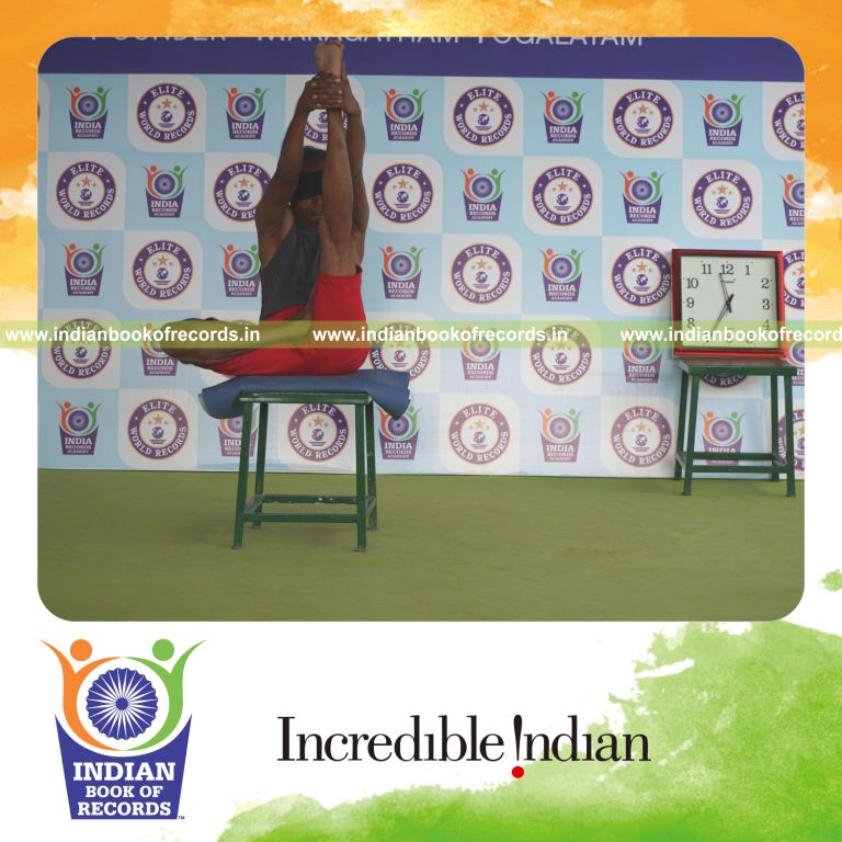 individual holding vama ardha padma krounchasana yoga pose blindfolded on a stool for record in Indian Book of Records