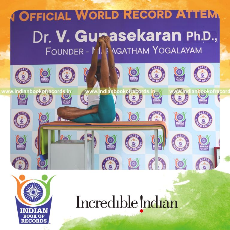 an individual holding vama ardha padma krounchasana yoga pose blindfolded on a table continuously for the longest duration with control and balance for a record in Indian Book of Records