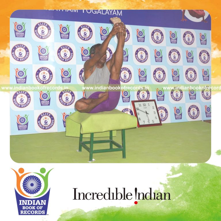 individual holding vama ardha padma krounchasana yoga pose on a stool for record in Indian Book of Records