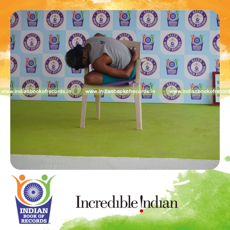 individual holding vama ardha padma marichyasana yoga pose blindfolded on a chair for record in Indian Book of Records