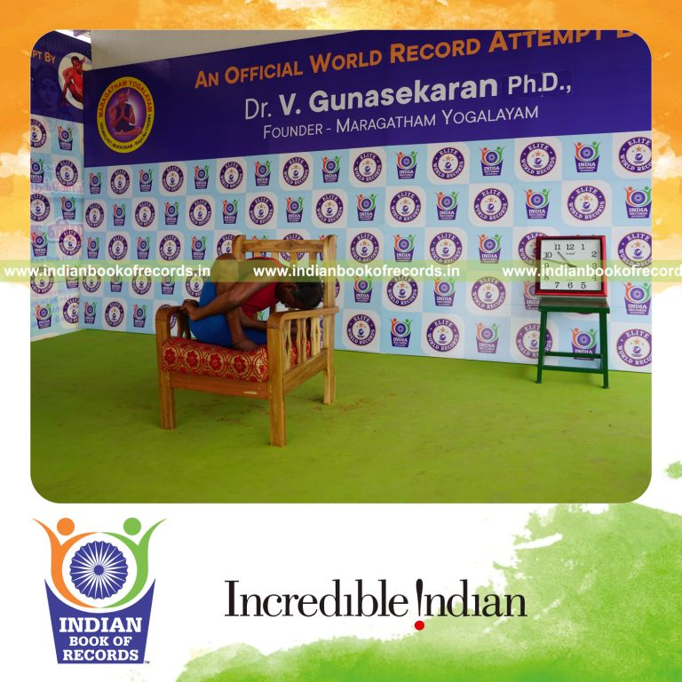 individual holding vama ardha padma marichyasana yoga pose on a chair for record in Indian Book of Records
