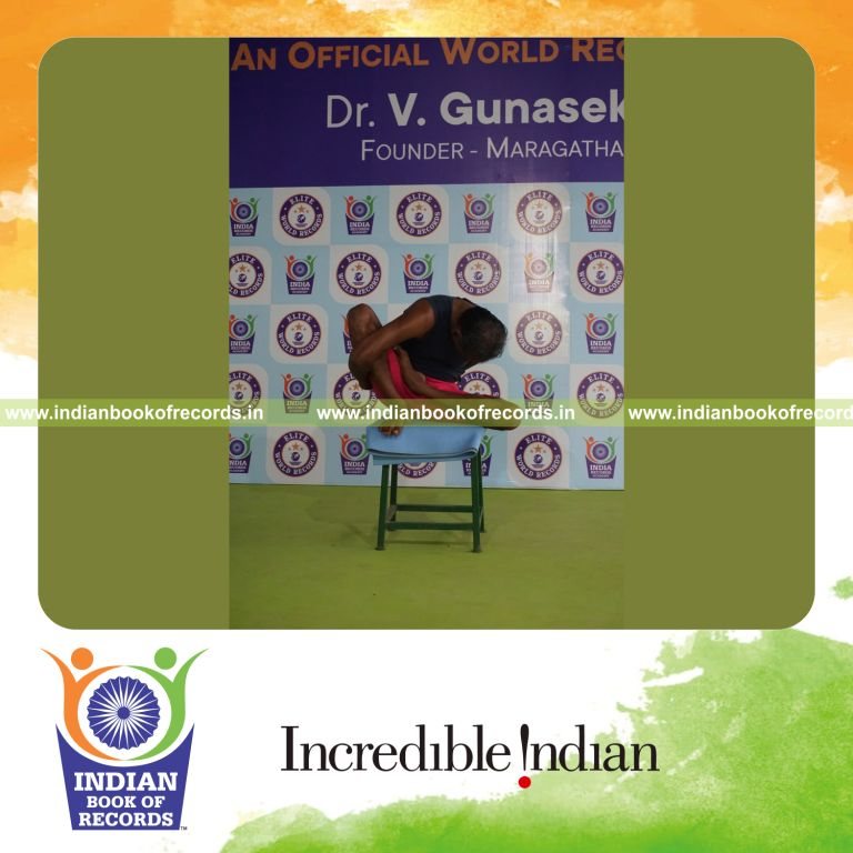 individual holding vama ardha padma marichyasana yoga pose on a stool for record in Indian Book of Records