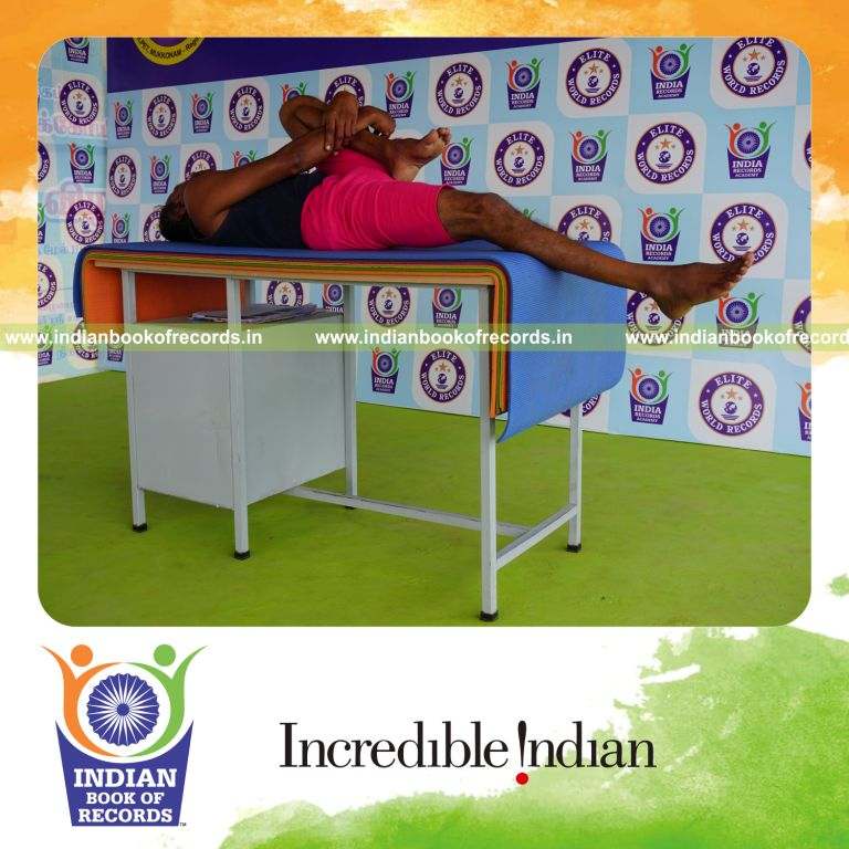 individual holding vama ardha pavanamuktasana yoga pose on a table for record in Indian Book of Records