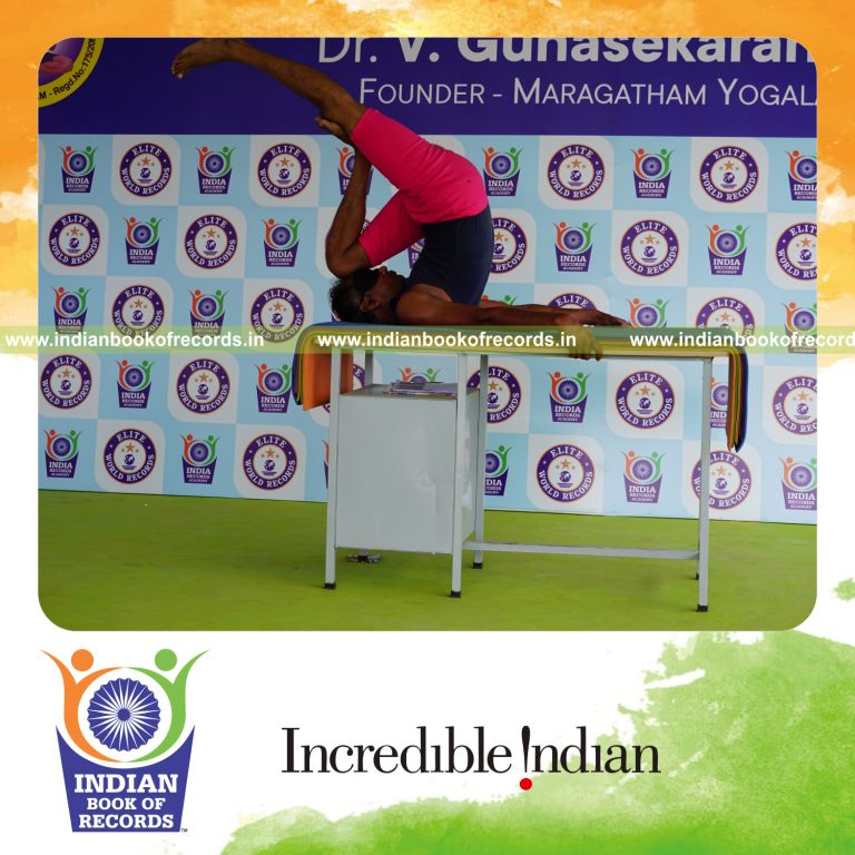 individual holding vama ardha salamba sarvangasana yoga pose blindfolded on a table for record in Indian Book of Records