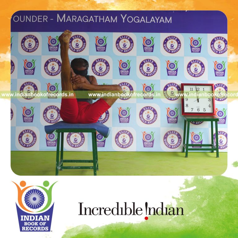 individual holding vama ardha urdhva mukha paschimottanasana yoga pose blindfolded on a stool for record in Indian Book of Records