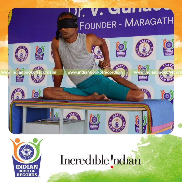 individual holding vama ardha vamadevasana yoga pose blindfolded on a table for record in Indian Book of Records
