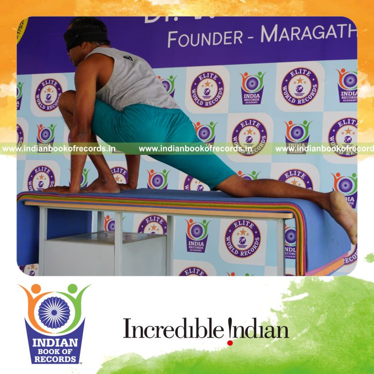 individual holding vama asva chanjalanasana yoga pose blindfolded on a table for record in Indian Book of Records