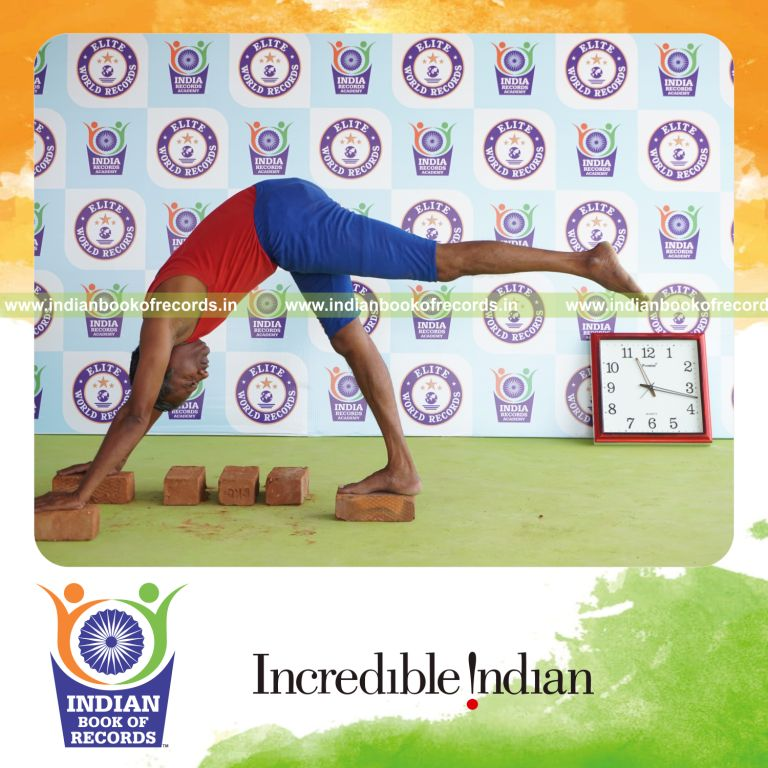 individual holding vama ekapada adho mukha svanasana yoga pose on bricks for record in Indian Book of Records
