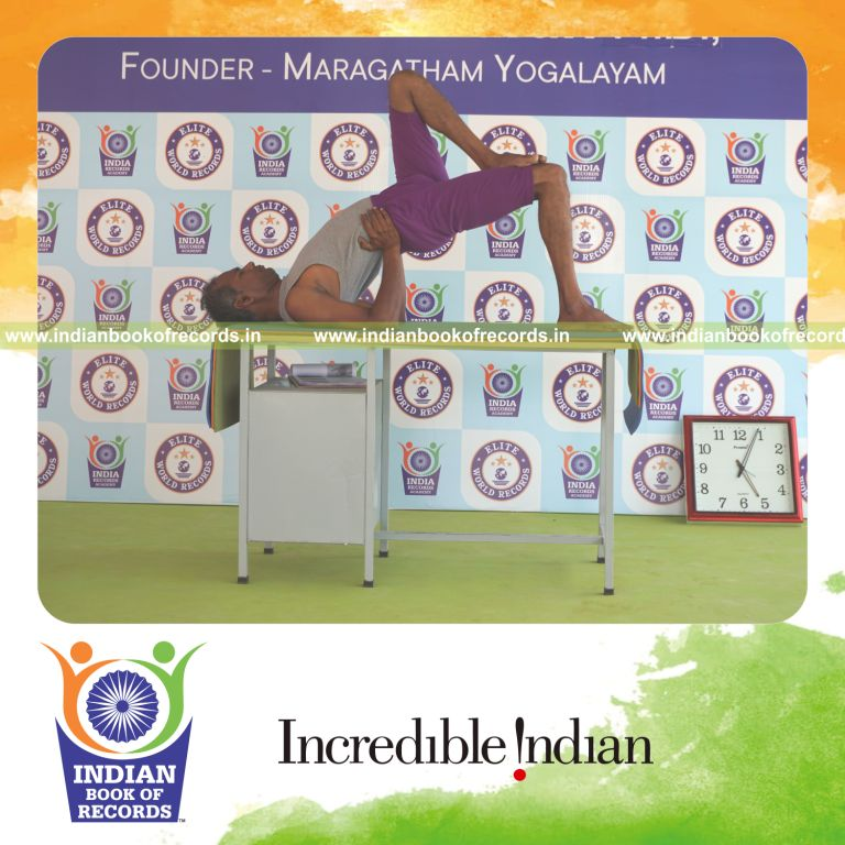 individual holding vama ekapada janu setu bandha sarvangasana yoga pose on a table for record in Indian Book of Records