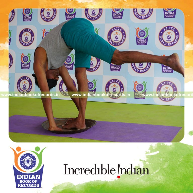 individual holding vama ekapada padahastasana yoga pose blindfolded on a brass plate for record in Indian Book of Records