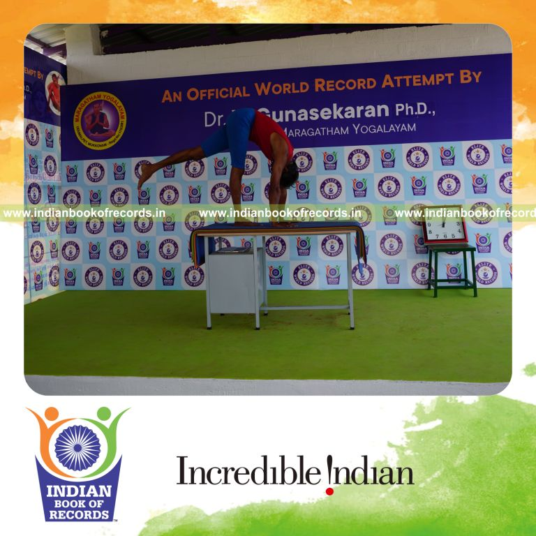individual holding vama ekapada padahastasana yoga pose blindfolded on a table for record in Indian Book of Records