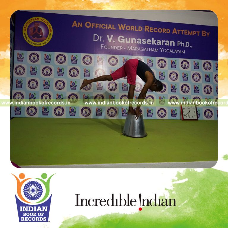 individual holding vama ekapada padahastasana yoga pose on a bucket for record in Indian Book of Records