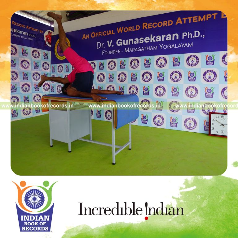 individual holding vama ekapada salamba sarvangasana yoga pose blindfolded on a table for record in Indian Book of Records