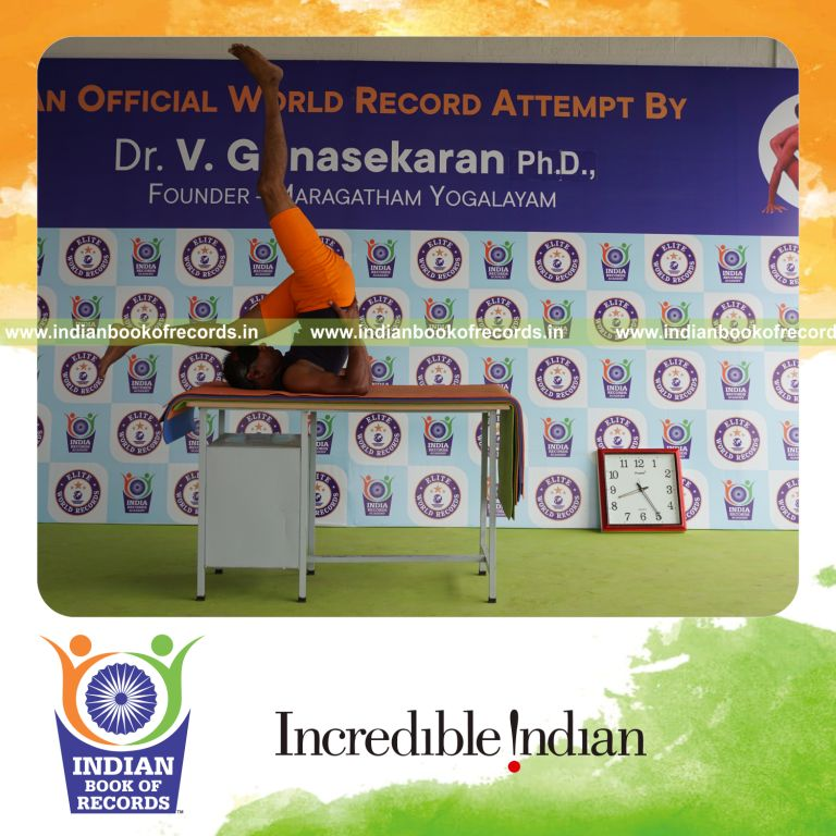 individual holding vama ekapada sarvangasana yoga pose blindfolded on a table for record in Indian Book of Records