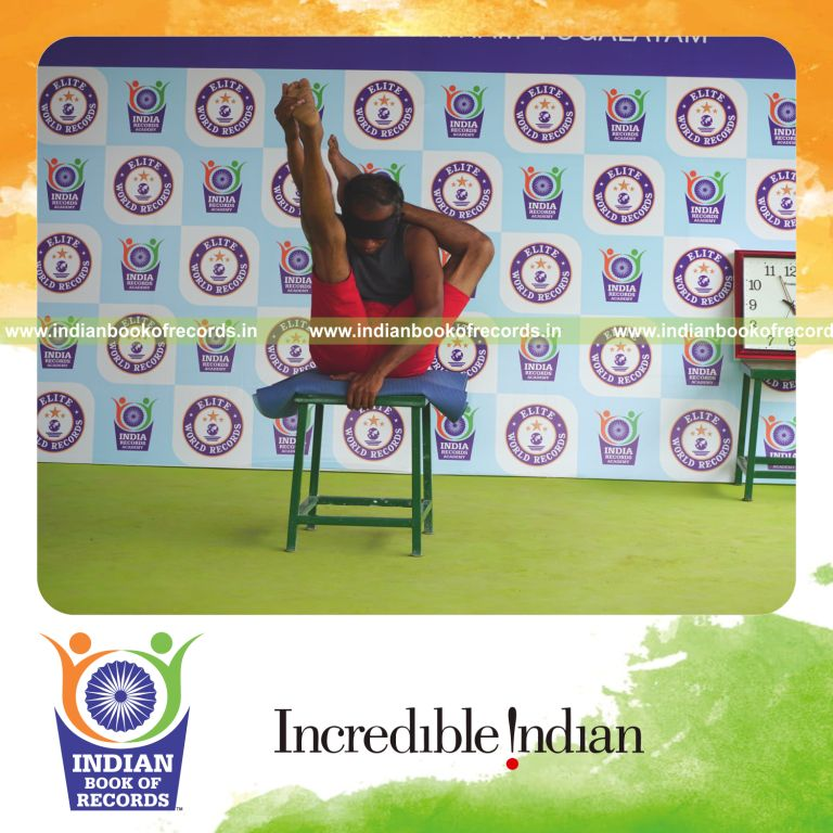 individual holding vama ekapada sirasa krounchasana yoga pose blindfolded on a stool for record in Indian Book of Records