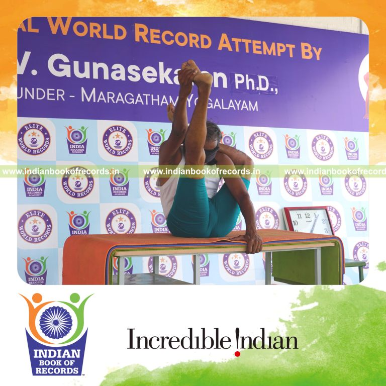 an individual holding vama ekapada sirasa krounchasana yoga pose blindfolded on a table continuously for the longest duration with control and balance for a record in Indian Book of Records