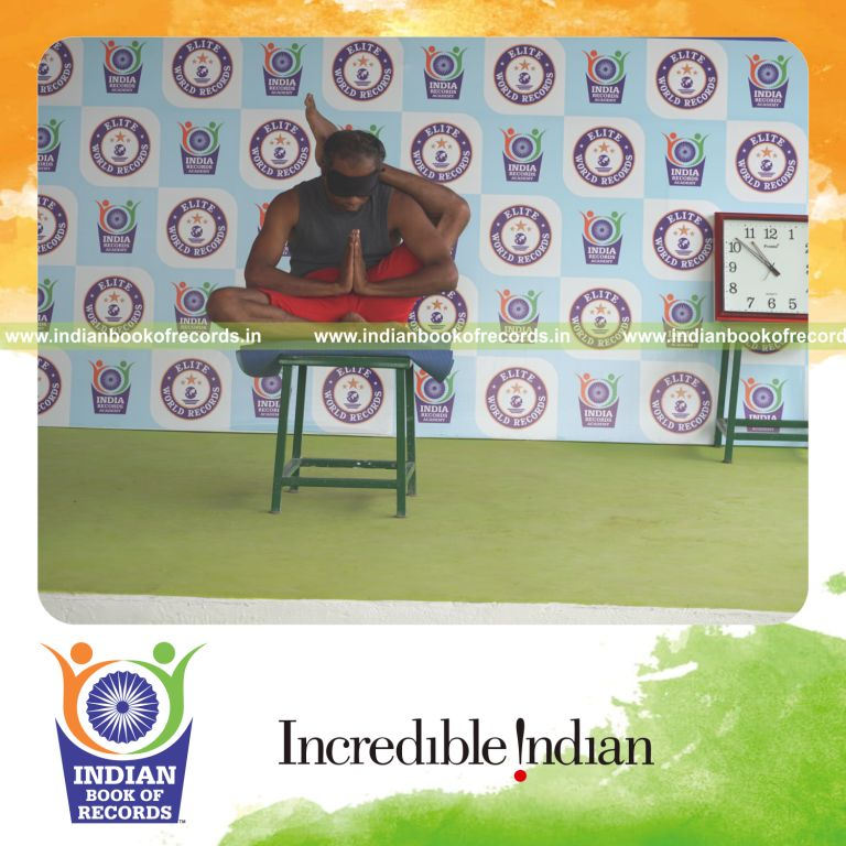 individual holding vama ekapada sirsasana yoga pose blindfolded on a stool for record in Indian Book of Records