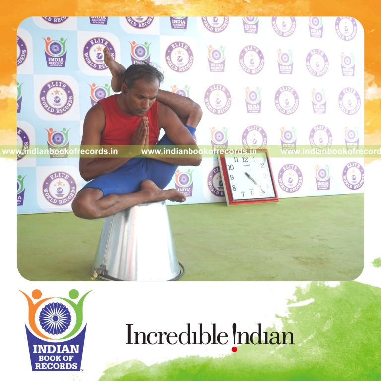 individual holding vama ekapada sirsasana yoga pose on a bucket for record in Indian Book of Records