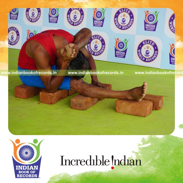 individual holding vama ekapada skandasana yoga pose on bricks for record in Indian Book of Records