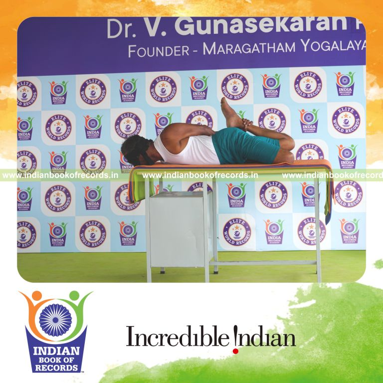 individual holding vama gherandasana second type yoga pose blindfolded on a table for record in Indian Book of Records