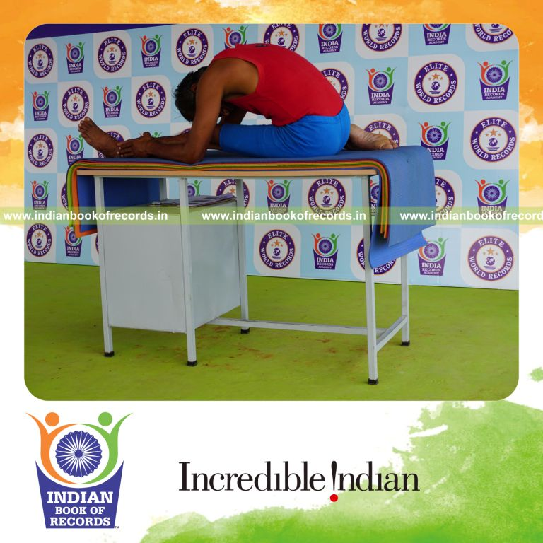 individual holding vama gomukha janu sirsasana yoga pose blindfolded on a table for record in Indian Book of Records