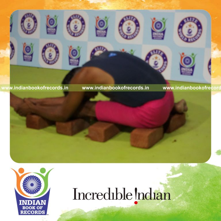 individual holding vama gomukha janu sirsasana yoga pose on bricks for record in Indian Book of Records