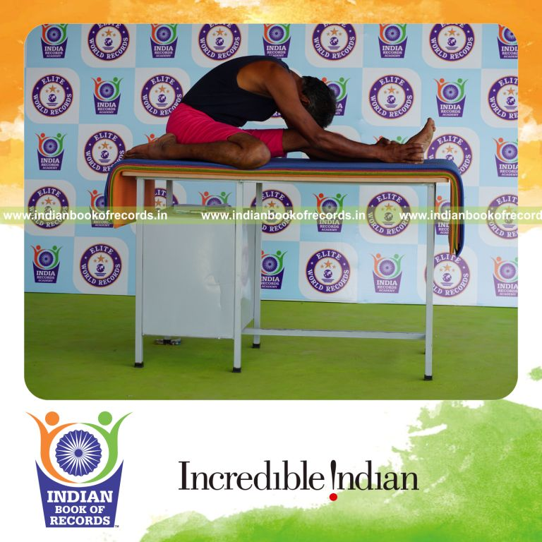 individual holding vama gomukha janu sirsasana yoga pose on a table for record in Indian Book of Records