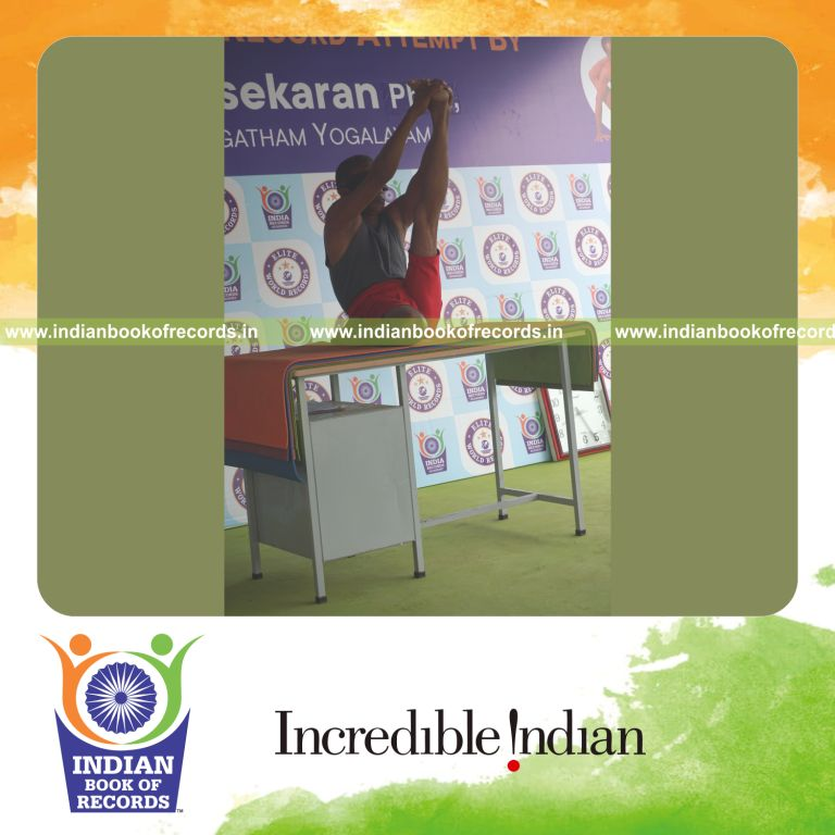 individual holding vama gomukha krounchasana yoga pose blindfolded on a table for record in Indian Book of Records