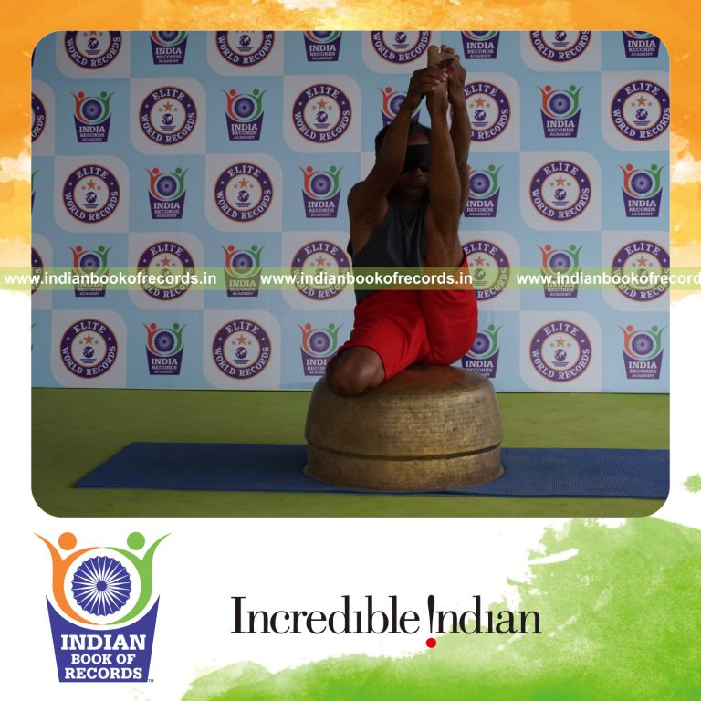 individual holding vama gomukha krounchasana yoga pose blindfolded on a vessel for record in Indian Book of Records