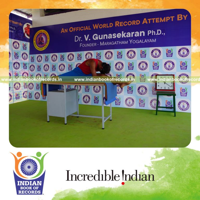 individual holding vama hanumana paschimottanasana yoga pose blindfolded on a table for record in Indian Book of Records