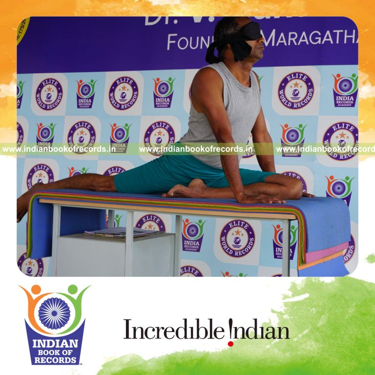 individual holding vama janu bhujangasana yoga pose blindfolded on a table for record in Indian Book of Records