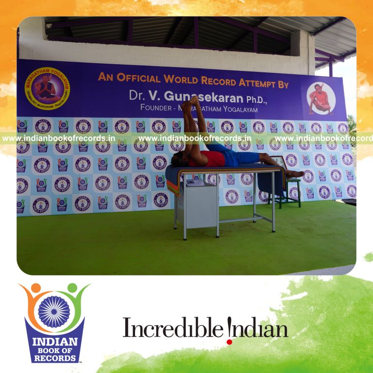 individual holding vama julasana yoga pose blindfolded on a table for record in Indian Book of Records