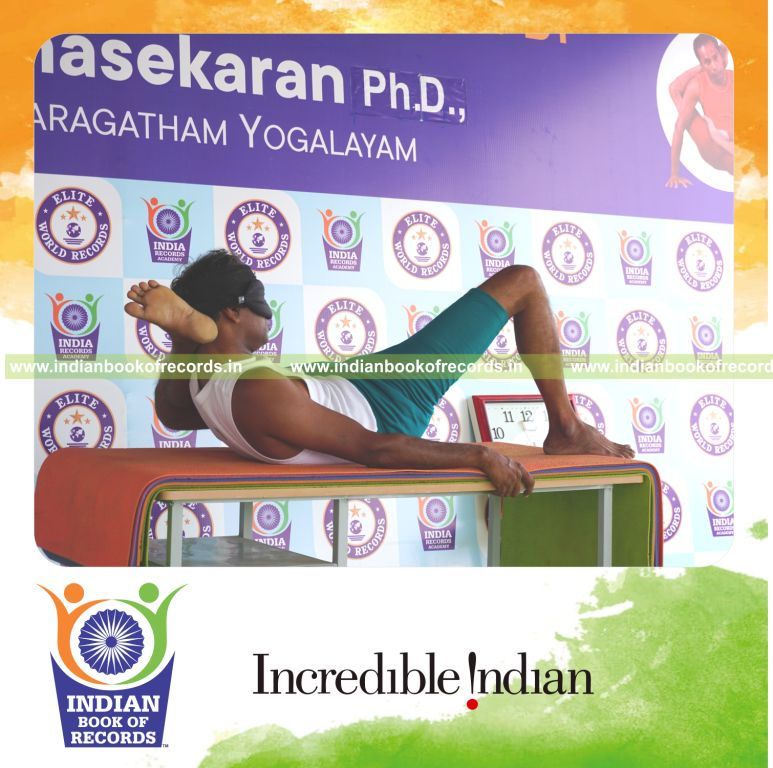 an individual holding vama kala bhairavasana yoga pose blindfolded on a table continuously for the longest duration with stability and control for a record in Indian Book of Records
