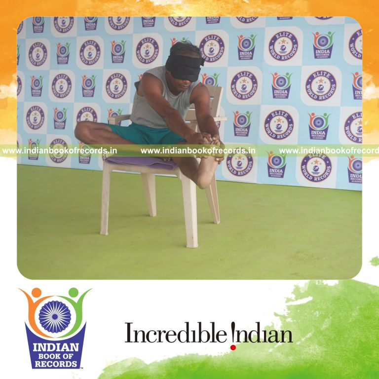 individual holding vama mahamudra yoga pose blindfolded on a chair for record in Indian Book of Records