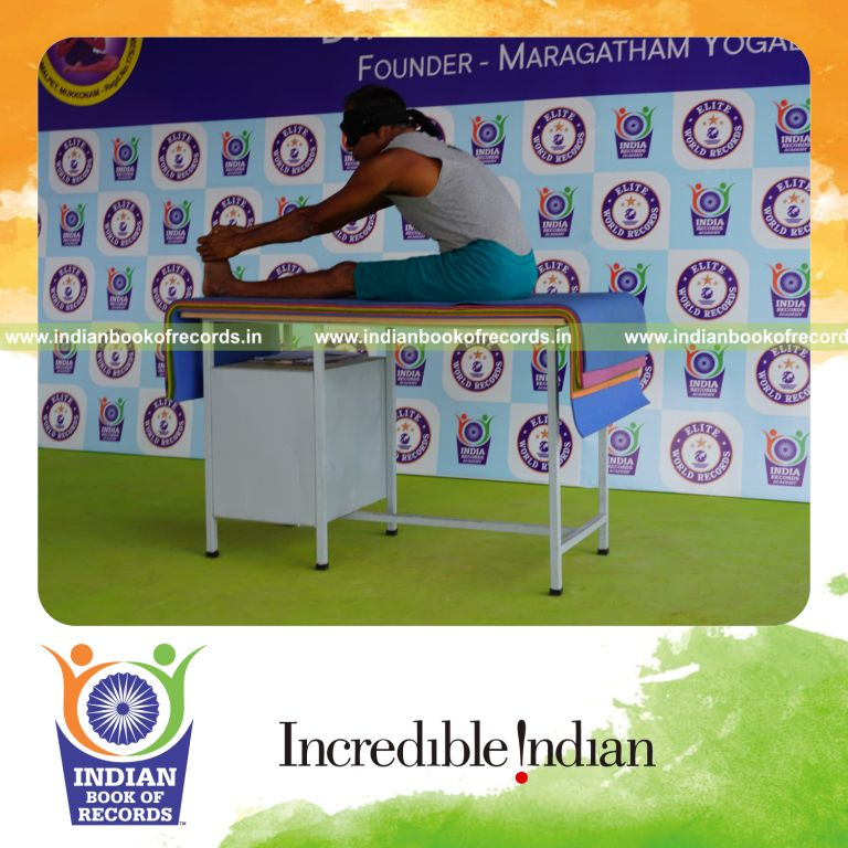 individual holding vama mahamudra yoga pose blindfolded on a table for record in Indian Book of Records