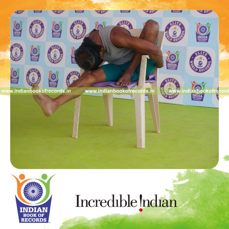 individual holding vama marichyasana yoga pose blindfolded on a chair for record in Indian Book of Records