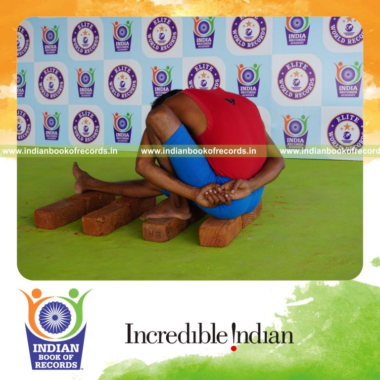 individual holding vama marichyasana yoga pose on bricks for record in Indian Book of Records