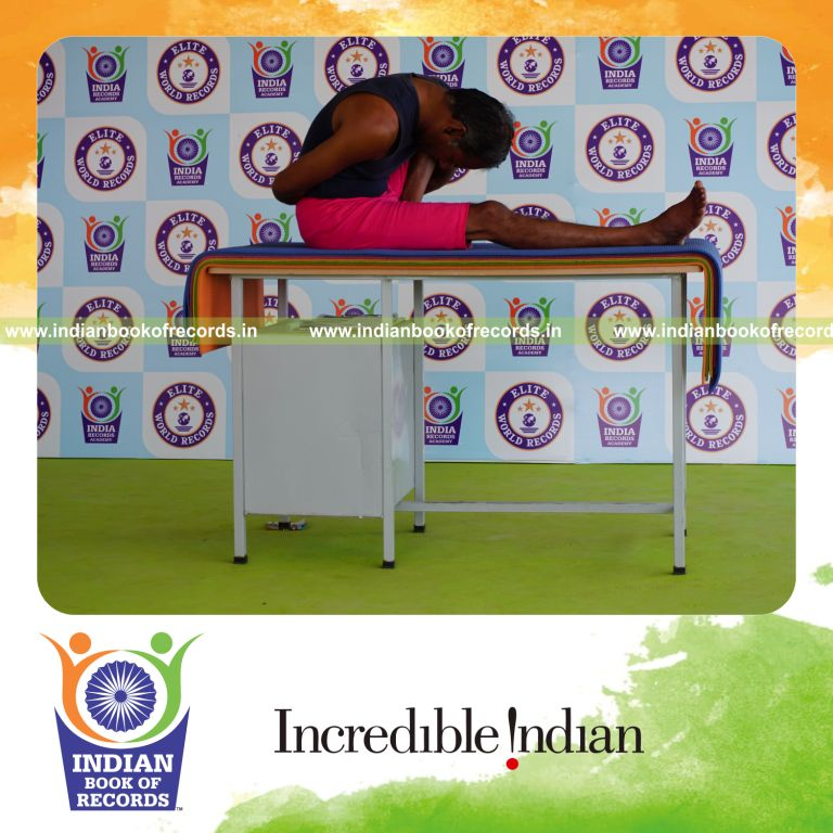 individual holding vama marichyasana yoga pose on a table for record in Indian Book of Records