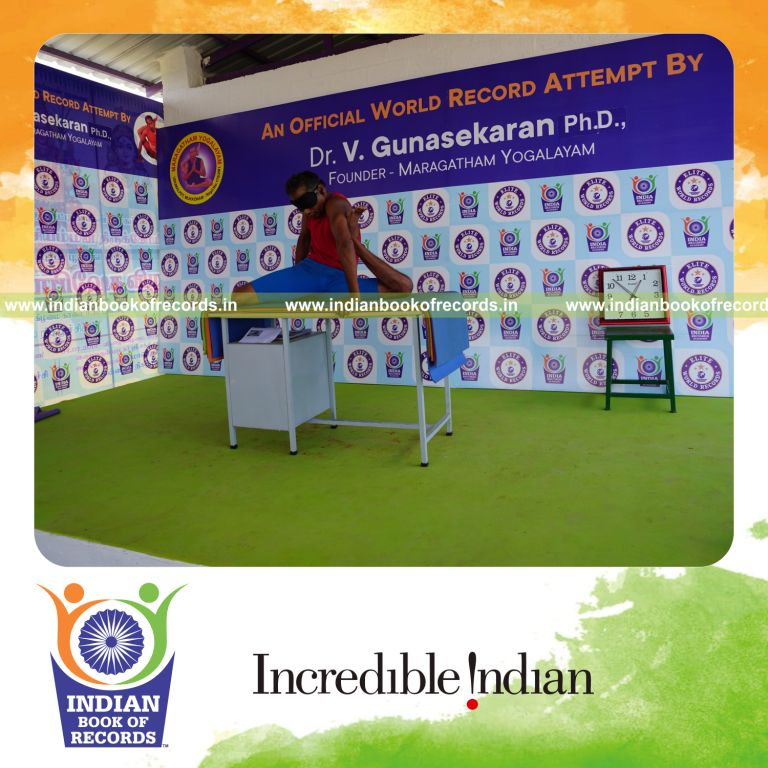 individual holding vama mrigasana yoga pose blindfolded on a table for record in Indian Book of Records