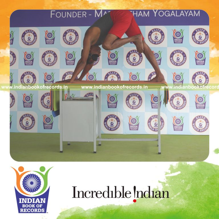 individual holding vama nasika purusta janu parsvasana yoga pose blindfolded on a table for record in Indian Book of Records