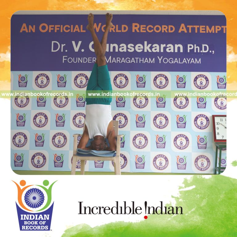 individual holding vama parivrtaikapata sirsasana yoga pose on a chair for record in Indian Book of Records