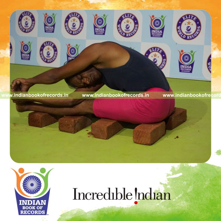 individual holding vama parivrtana janu sirsasana yoga pose on bricks for record in Indian Book of Records