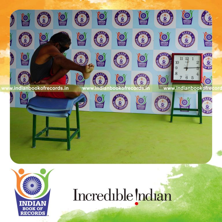 individual holding vama parivrtta ardha matsyendrasana yoga pose blindfolded on a stool for record in Indian Book of Records