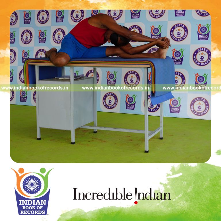 individual holding vama parivrtta gomukha janu sirsasana yoga pose blindfolded on a table for record in Indian Book of Records