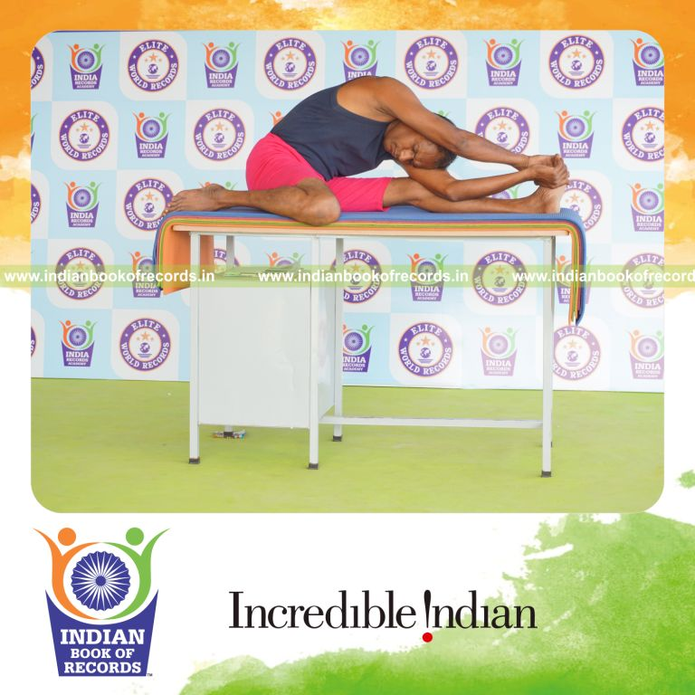 individual holding vama parivrtta gomukha janu sirsasana yoga pose on a table for record in Indian Book of Records