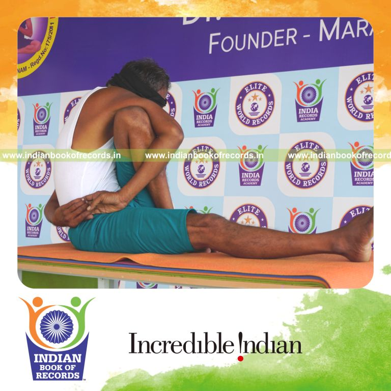 an individual holding vama parivrtta marichyasana yoga pose blindfolded on a table continuously for the longest duration with control and balance for a record in Indian Book of Records