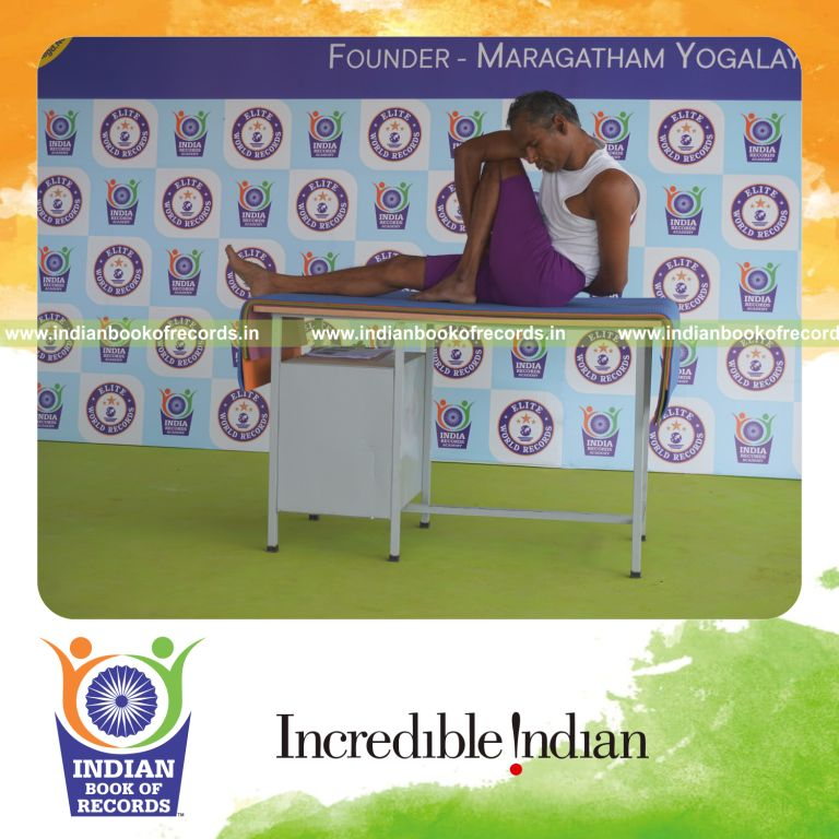 individual holding vama parivrtta marichyasana yoga pose on a table for record in Indian Book of Records