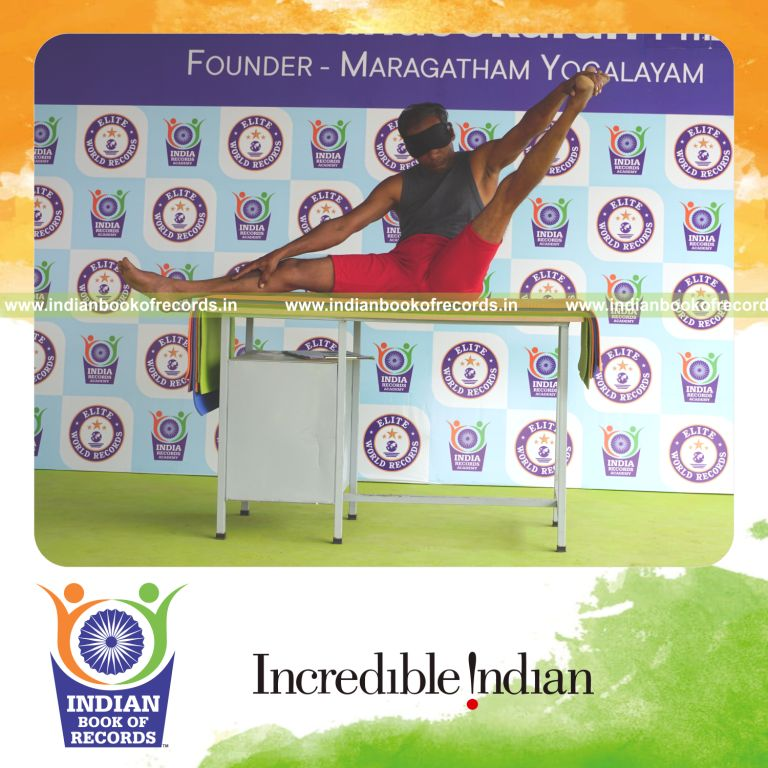 individual holding vama parshwa akarna dhanurasana yoga pose blindfolded on a table for record in Indian Book of Records