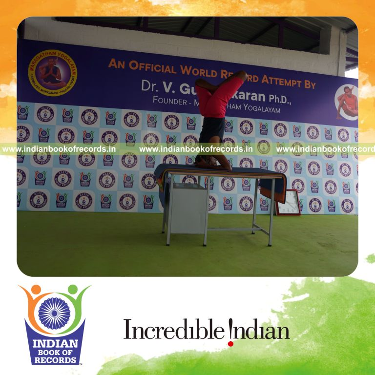 individual holding vama parshwa padma sirsasana yoga pose on a table for record in Indian Book of Records